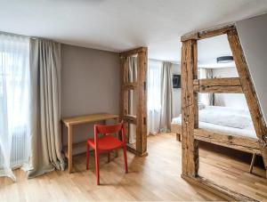 um quarto com um beliche e uma cadeira vermelha em Gasthof Löwen Tosters em Feldkirch