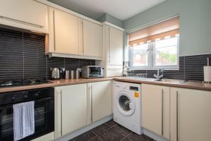 a kitchen with white cabinets and a washing machine at Grange Way in Bowburn