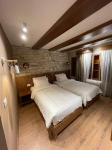 2 bedden in een slaapkamer met een bakstenen muur bij Palorto Hotel in Gjirokastër