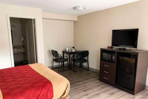 a hotel room with a bed and a flat screen tv at Econo Lodge in Vancouver