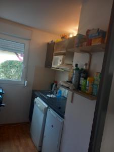 eine kleine Küche mit einem weißen Kühlschrank und einem Fenster in der Unterkunft Villas du lac Appart 4 à 6 personnes in Soustons