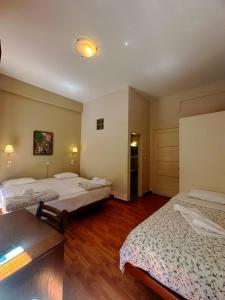 een kamer met 3 bedden en een houten vloer bij Vassilikon Hotel in Loutraki