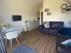 a living room with a couch and a table at 1-Bed pod cabin in beautiful surroundings Wrexham in Wrexham