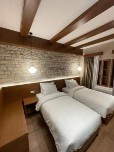 a room with two beds and a brick wall at Palorto Traditional Hotel in Gjirokastër