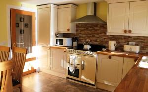 a kitchen with white cabinets and a stove top oven at Fairy Glen Cottage in Uig