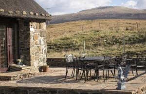 a table and chairs on a patio with a view of a hill at Fairy Glen Cottage in Uig