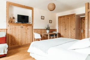 1 dormitorio con 1 cama, TV y mesa en Golf du Rochat en Les Rousses