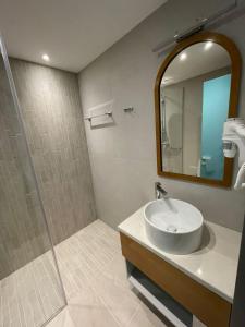 een badkamer met een wastafel en een douche met een spiegel bij Palorto Traditional Hotel in Gjirokastër
