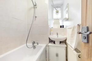 a white bathroom with a sink and a shower at Central & Cosy 2BD Flat near Canary Wharf in London