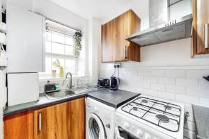 a kitchen with a white stove top oven next to a sink at Central & Cosy 2BD Flat near Canary Wharf in London