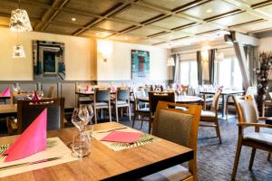 uma sala de jantar com mesas e cadeiras com guardanapos cor-de-rosa em Golf du Rochat em Les Rousses
