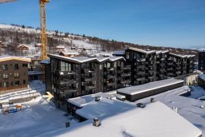 un complesso di appartamenti nella neve con una gru di Tiltalende og romslig leilighet a Beitostøl