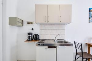 una cocina con armarios blancos y fregadero en Johnhara Studios & Apartments en Ialyssos