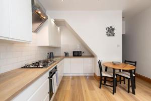 a kitchen with white cabinets and a wooden table at Trafalgar Terrace in Darlington