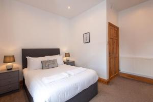 a bedroom with a large white bed with two lamps at Trafalgar Terrace in Darlington