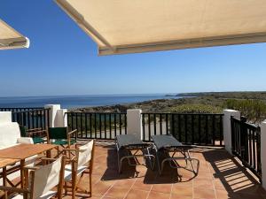 un patio con mesas y sillas y vistas al océano en ALDEAMAR F1 by SOM Menorca, en Son Parc