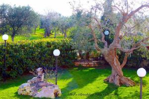 a statue sitting in the grass next to a tree at B&B Villa Cassandra in Castellana Grotte