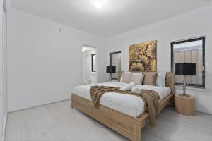 a white bedroom with a large bed and a window at Modern Family Escapes Shopping at your doorstep in Perth