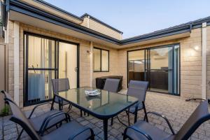 a patio with a glass table and chairs at Modern Family Escapes Shopping at your doorstep in Perth