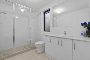 a white bathroom with a toilet and a glass shower at Modern Family Escapes Shopping at your doorstep in Perth