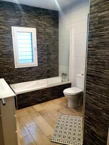 een badkamer met een bad, een toilet en een raam bij LA BRISA in Cádiz