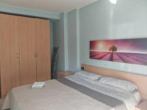 a bedroom with a bed with a large painting on the wall at S'Abanell Central Park seafront apartment in Blanes