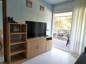 una sala de estar con TV en un centro de entretenimiento de madera en S'Abanell Central Park seafront apartment en Blanes