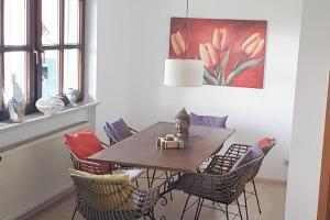 a dining room table with chairs and a painting at City-close oasis in the green in Deggendorf