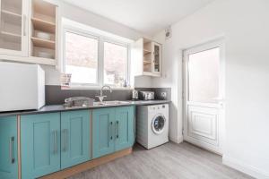 a kitchen with blue cabinets and a washing machine at Cosy home near Port of Hull in Hull