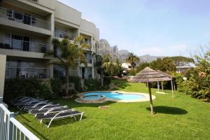 un patio con sillas y una sombrilla junto a un edificio en Stunning Sea View Apartment - Camps Bay en Ciudad del Cabo