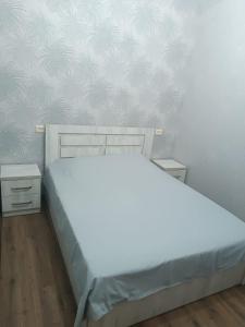 a bedroom with a white bed and two night stands at Palms in Kutaisi in Kutaisi