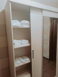a bathroom with a closet with white towels and a mirror at Palms in Kutaisi in Kutaisi