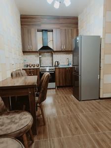 a kitchen with a refrigerator and a table and chairs at Palms in Kutaisi in Kutaisi