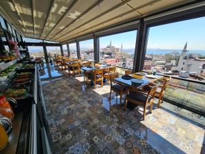 um restaurante com mesas e cadeiras e janelas grandes em Anthemis Hotel em Istambul