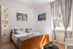 a white bedroom with a bed and a window at Apartment Porat in Dubrovnik