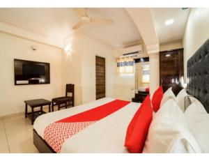 a bedroom with a large bed with red pillows at Hotel Grand Apple, Ahmedabad in Ahmedabad