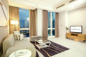 a living room with a couch and a tv at Fraser Residence Sudirman Jakarta in Jakarta