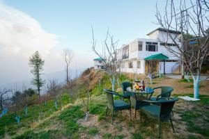 a table and chairs on a hill with a house at Crested View Kufri -Orchard Villa in Kūfrī