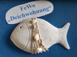 Ein weißer Fisch mit einem Schild drauf. in der Unterkunft Ferienwohnungen Brasse in Dornumersiel