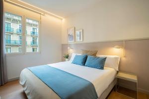 a bedroom with a large bed with blue pillows at Fisa Rentals Ramblas Apartments in Barcelona