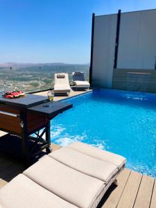 una piscina con una mesa y una copa de vino en Galilee Hills - Resort & Suites, en Maghār