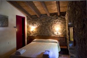 a bedroom with a bed and a stone wall at Mas Molera Turisme Rural in Sant Joan les Fonts