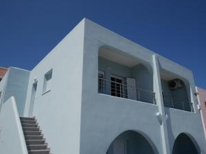 una casa blanca con escaleras y un cielo azul en Roza's Family House, en Imerovigli
