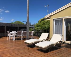 a deck with white chairs and a table and chairs at 4 bedroom family holiday home with large deck in Blairgowrie
