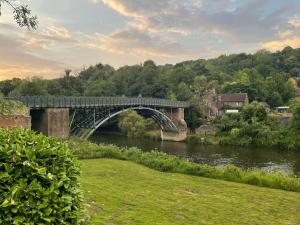 een stenen brug over een rivier met een grasveld bij Carriage 2 - Coalport Station Holidays in Telford