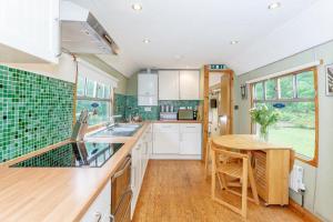 a kitchen with white cabinets and a wooden table at Carriage 2 - Coalport Station Holidays in Telford