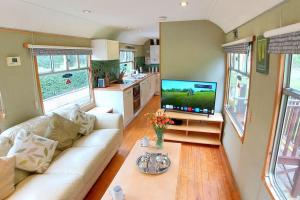 ein Wohnzimmer mit einem weißen Sofa und einem TV in der Unterkunft Carriage 2 - Coalport Station Holidays in Telford