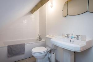 a white bathroom with a toilet and a sink at Stylish Cottage in the Pewsey Vale in Marlborough