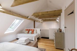 1 dormitorio en el ático con 2 camas y ventana en Stylish Cottage in the Pewsey Vale en Marlborough