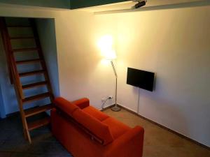 a living room with an orange couch and a television at Villa Oliva in Canino